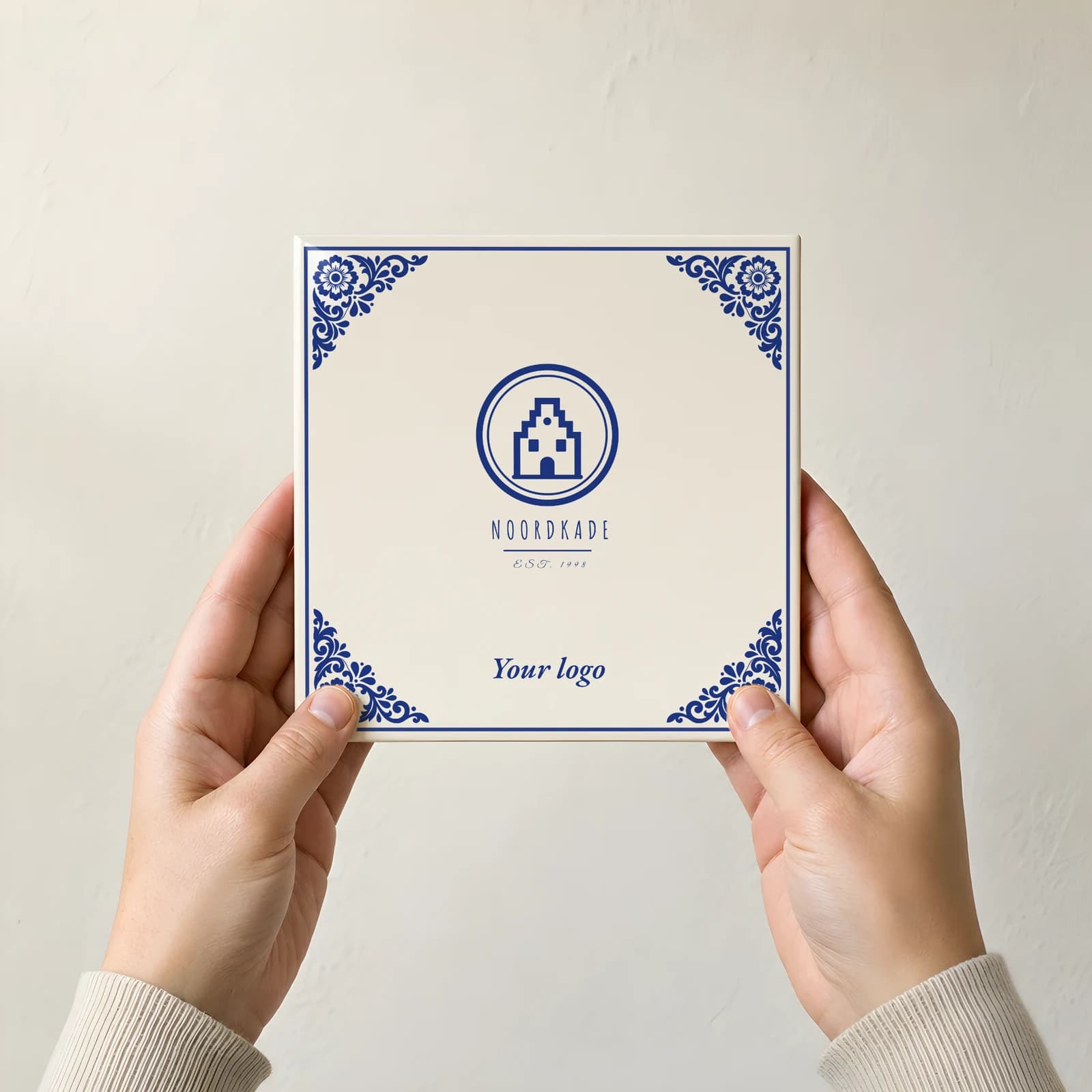 A tile carrying a sample logo, held in two hands